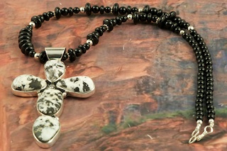 Stunning Cross Pendant featuring Genuine White Buffalo Turquoise set in Sterling Silver. The Cross Pendant is on a Genuine Black Onyx Necklace with Sterling Silver Beads and Clasp. This Beautiful Stone is formed from the minerals Calcite and Iron. It is mined near Tonopah Nevada. Created by Navajo Artist Evelyn Yazzie. Signed by the artist. 